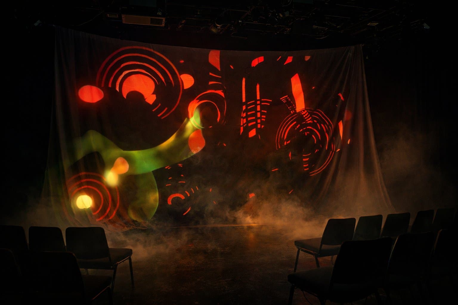Projected artwork on a draped screen above seating