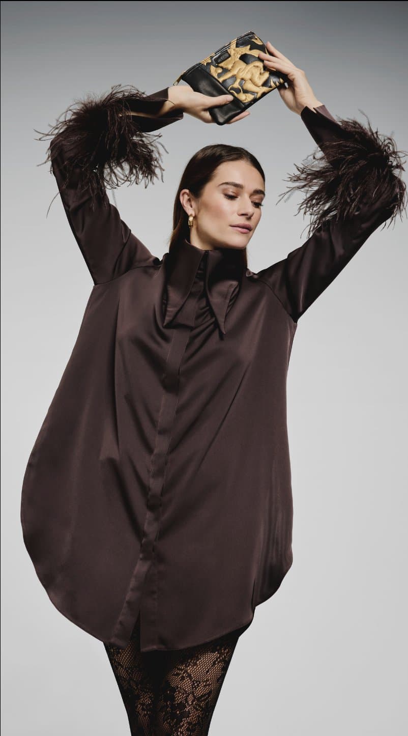 Campaign shot: model holding a gilded leather clutch overhead